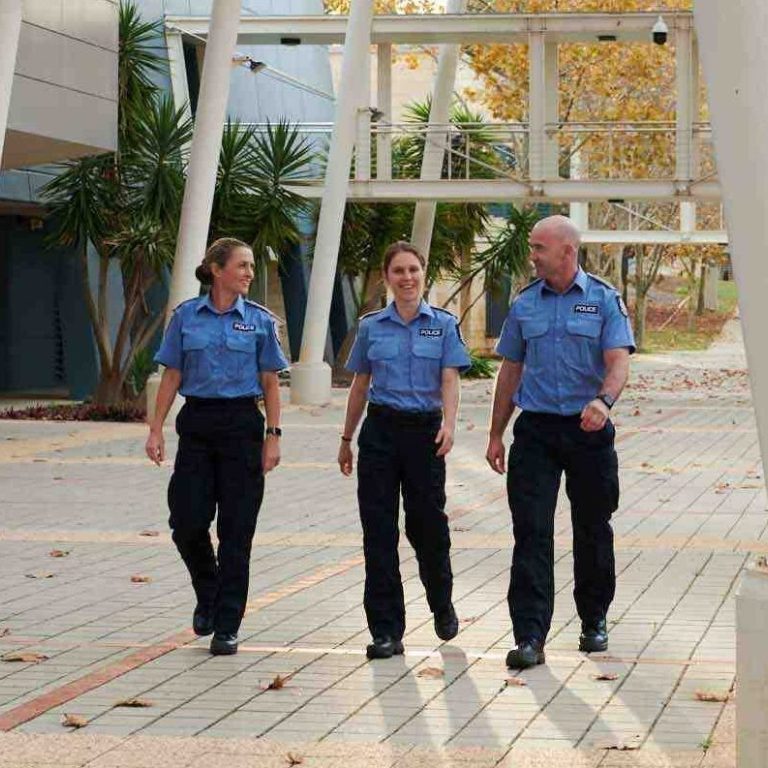 Two female and one male police officers walking through a courtyard